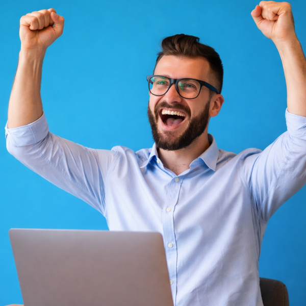 Cette image montre un jeune homme souriant, assis à une table, utilisant son smartphone avec une expression joyeuse. Il porte un pull jaune vif qui contraste avec le fond bleu, créant une ambiance dynamique et moderne. Cette scène illustre une expérience utilisateur positive, liée à l’utilisation d’une application ou d’un service digital, évoquant la simplicité, la satisfaction et la connexion.